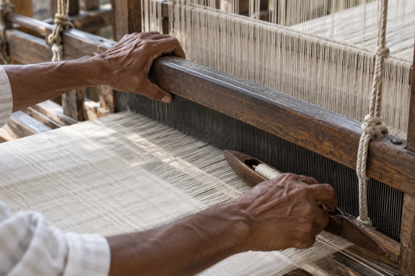 Illustrative hands weaving fabric on an Indian handloom